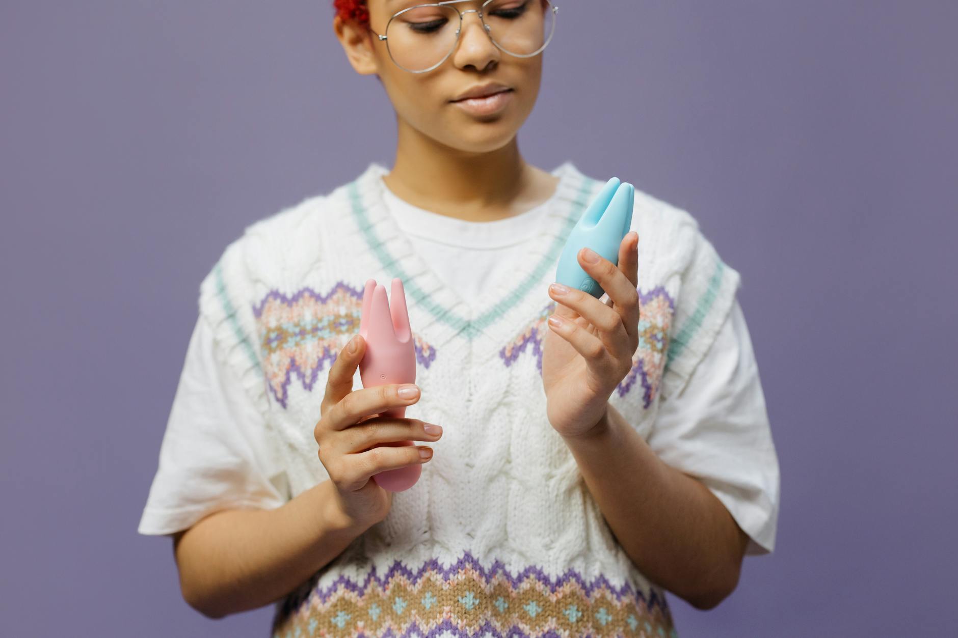 青とピンクのシリコン製バイブレーターを思慮深く手に持つ女性
